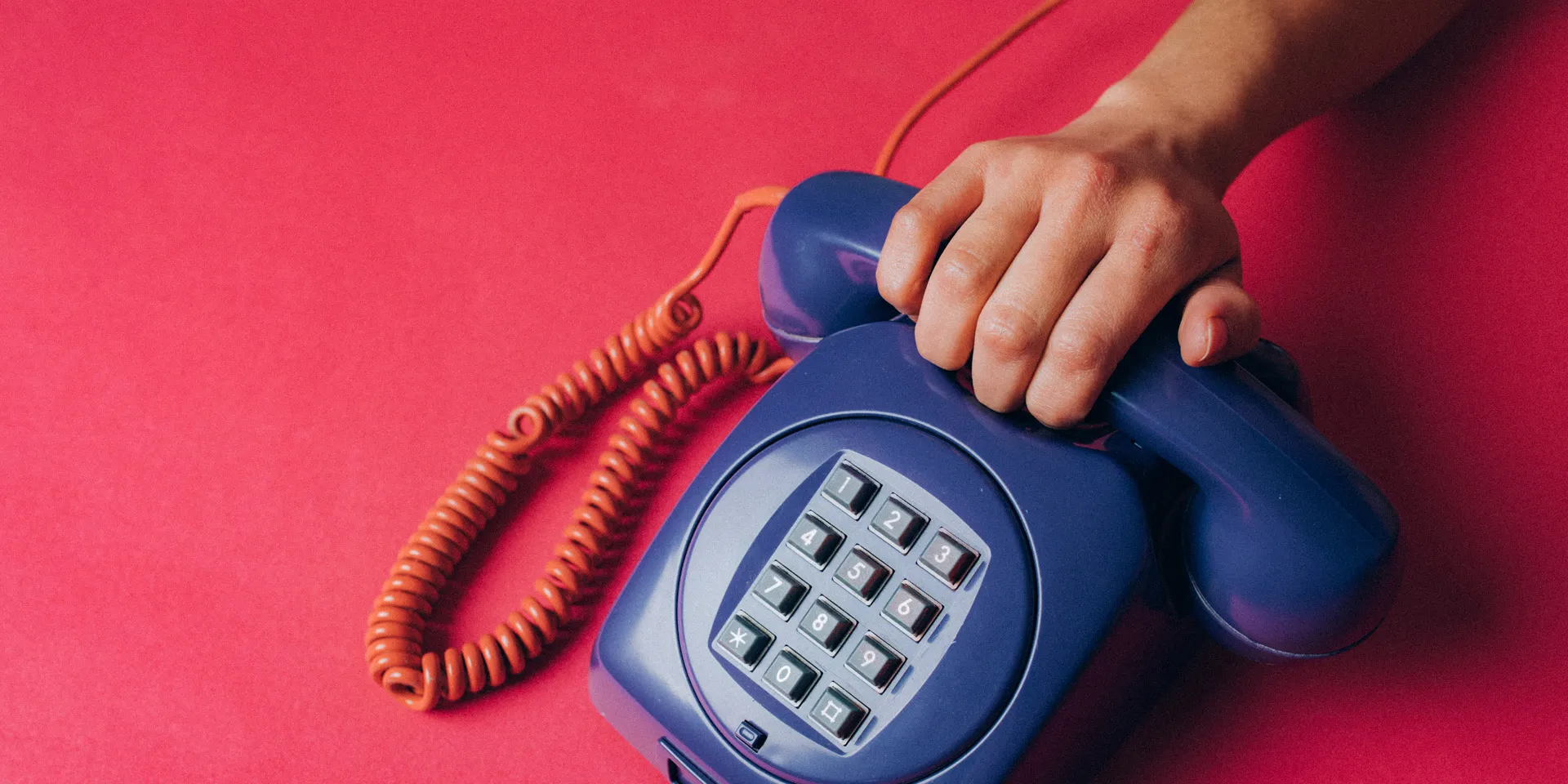 Mano tomando el tubo de un teléfono antiguo